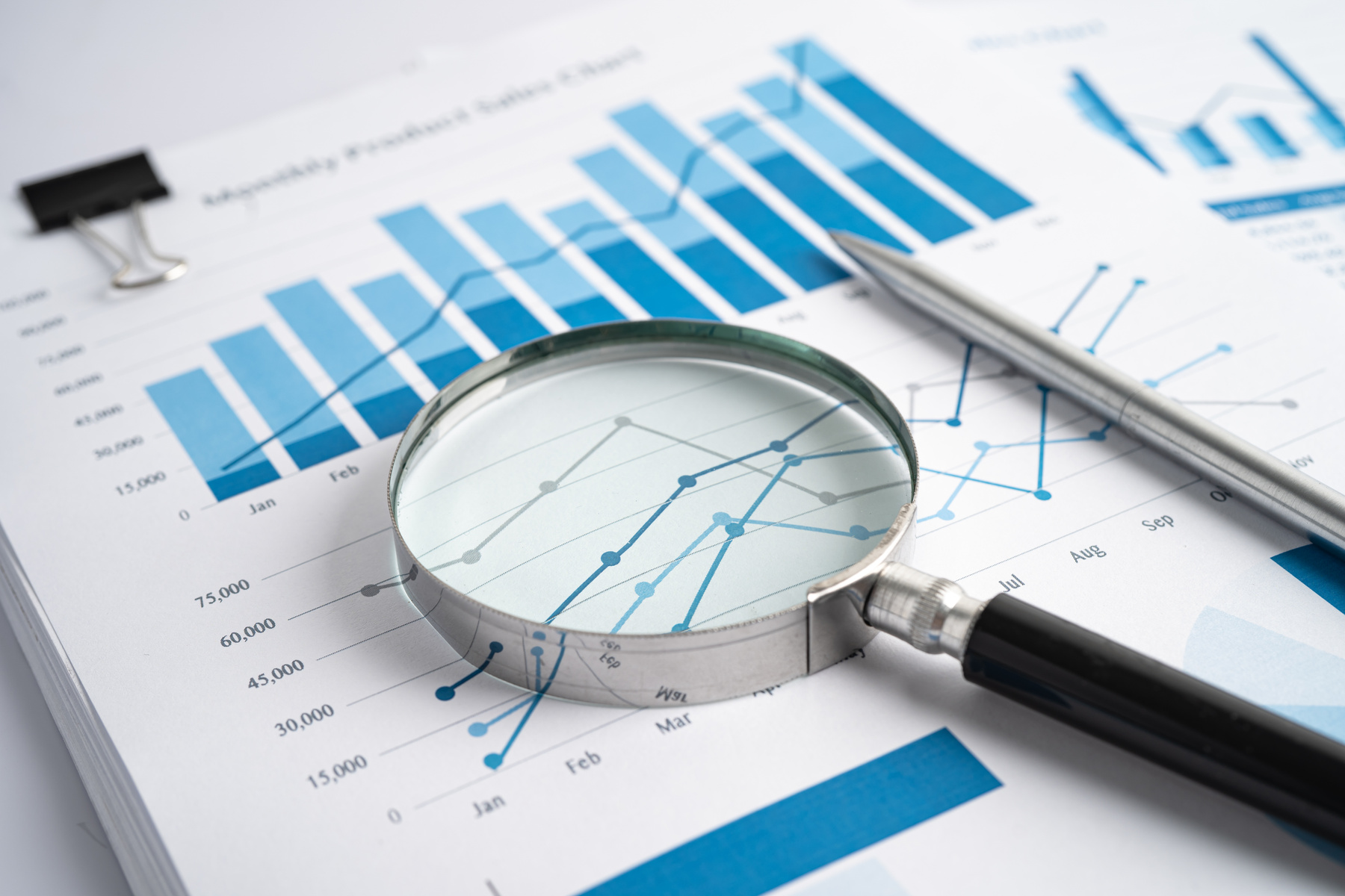 Magnifying Glass on Charts Graphs Paper. Financial Development,